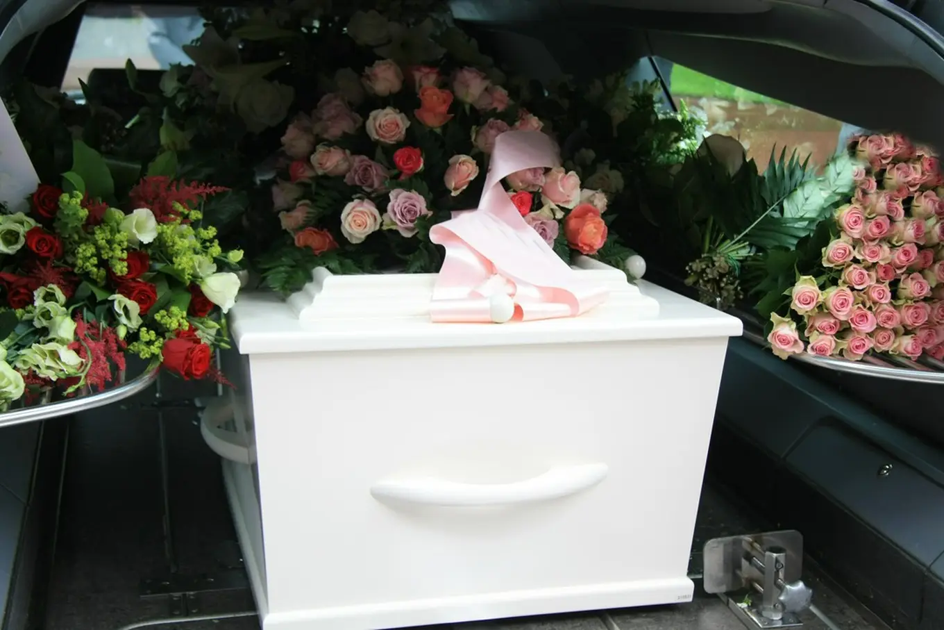 biała trumna w samochodzie pogrzebowym